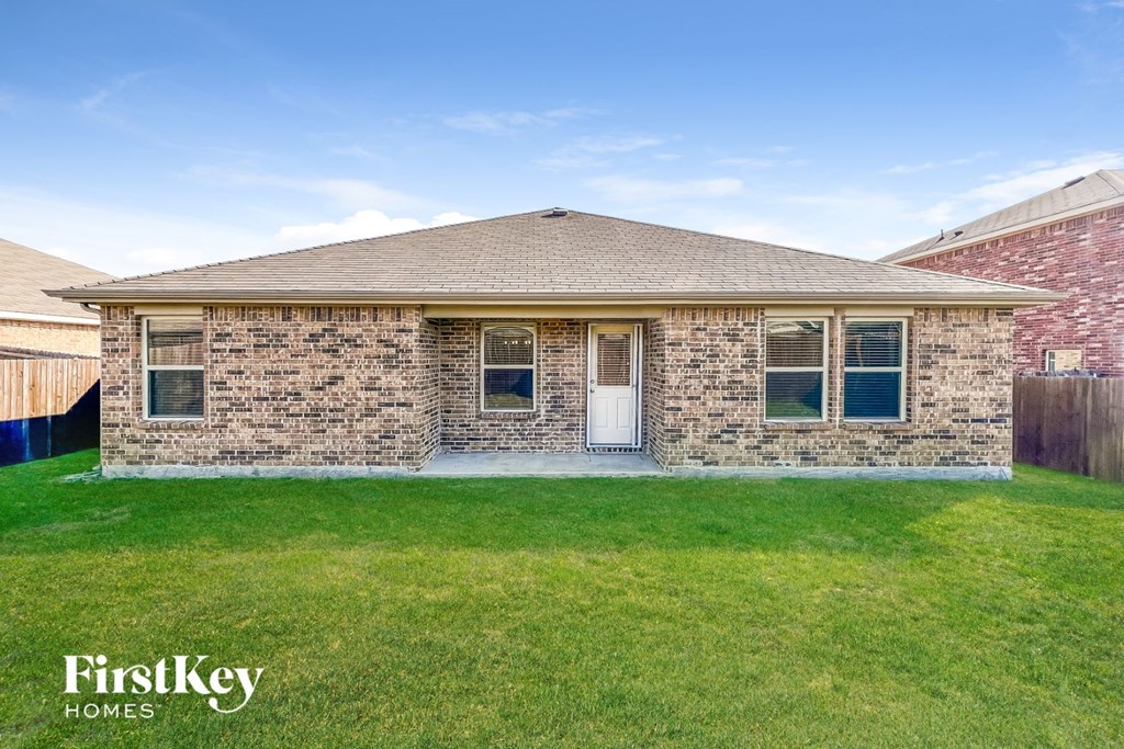 a small brick house with a lawn and grass