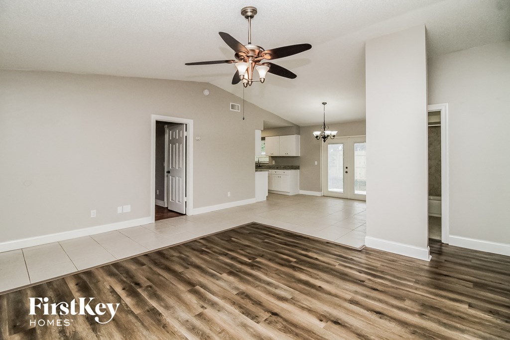 A spacious room with a ceiling fan and wooden flooring.