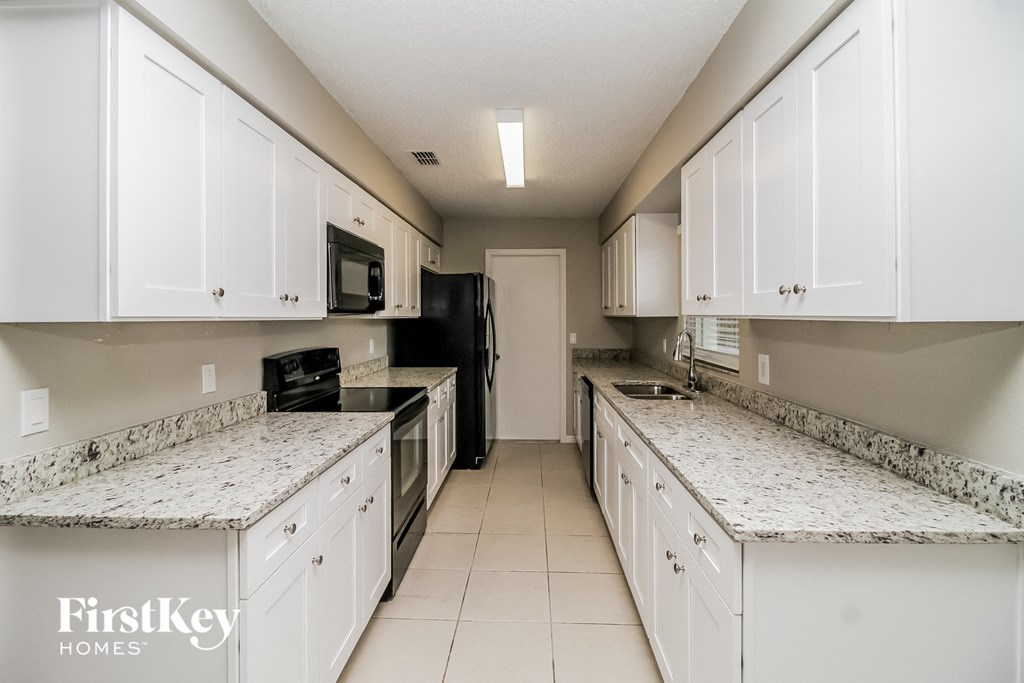 A kitchen with white cabinets and granite countertops.