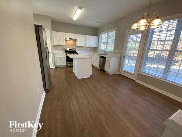 an empty living room and kitchen with wood floors