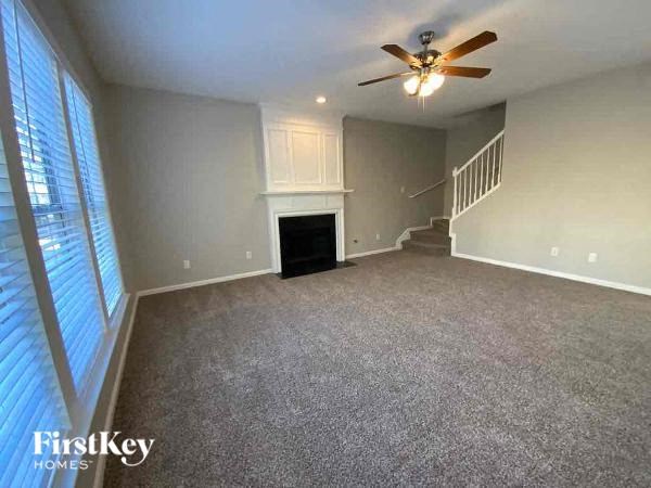 an empty living room with a ceiling fan and a large window