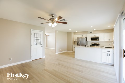 A spacious kitchen and living room with a ceiling fan and light fixture.