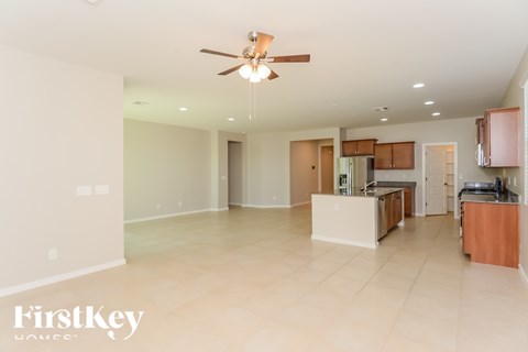 A spacious kitchen and living room with a ceiling fan and lighting fixtures.