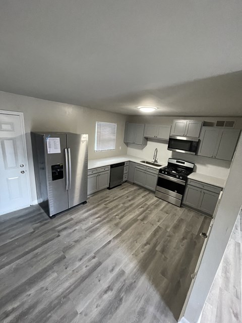 a renovated kitchen with gray cabinets and a stainless steel refrigerator