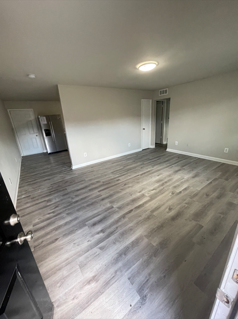 a empty living room with wood floors and white walls