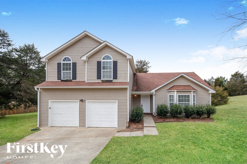 a beige house with a garage and a lawn