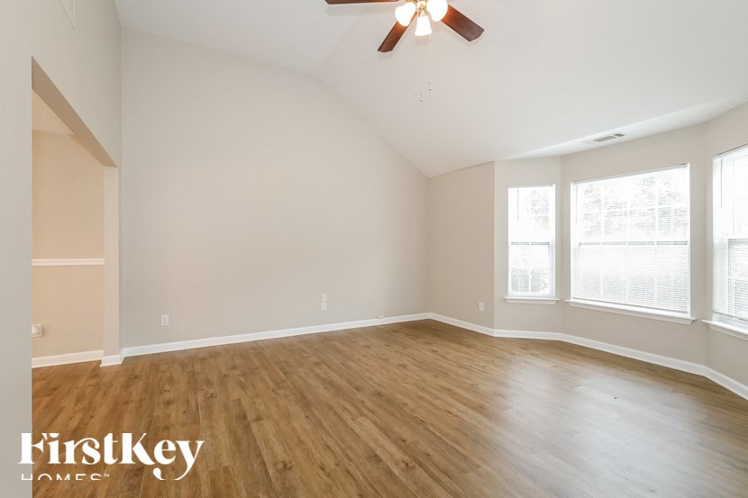 the spacious living room with hardwood floors and a ceiling fan