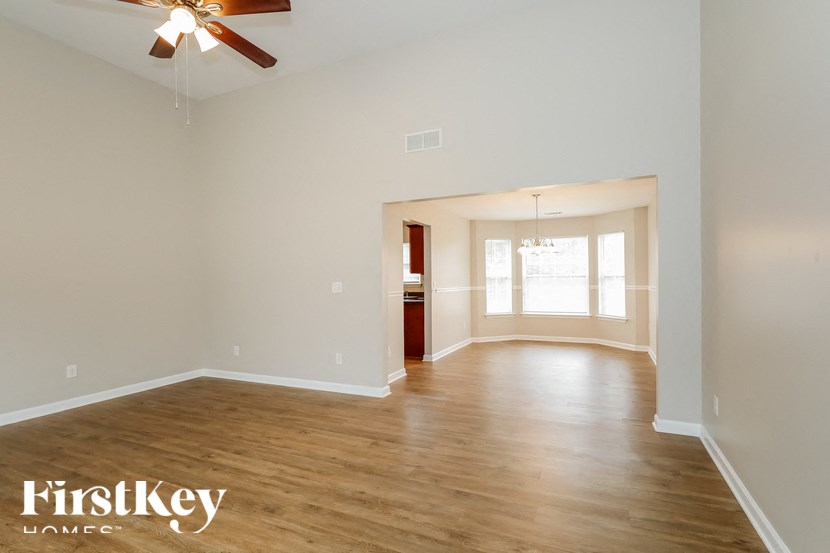an empty living room with wood floors and a ceiling fan