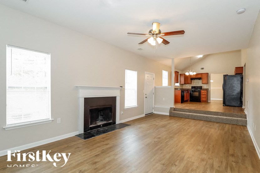 an empty living room with a fireplace and a ceiling fan
