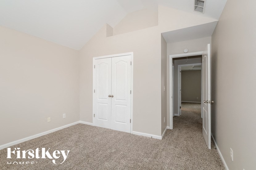 a bedroom with white doors and carpet and a hallway to a closet