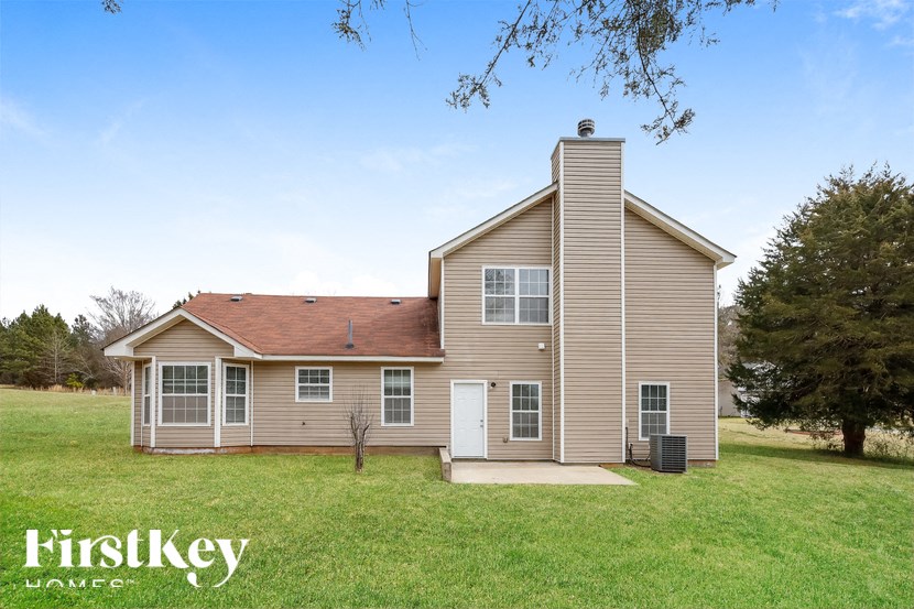 the front of a house with a lawn and a tree
