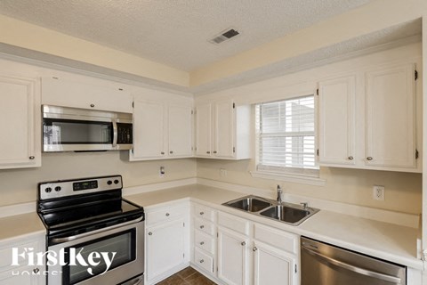 A kitchen with white cabinets and a stove top oven.