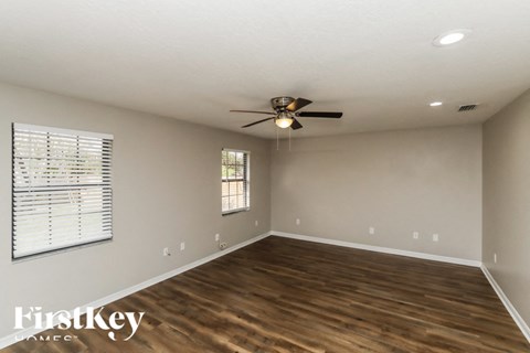 A spacious room with wooden flooring and a ceiling fan.