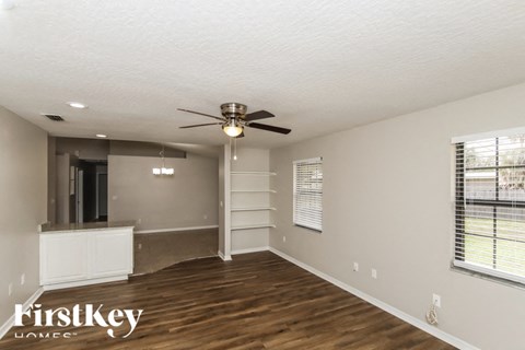 A spacious room with a ceiling fan and wooden flooring.