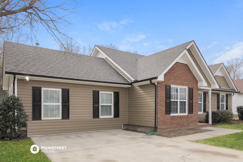 the front view of a brown house with a driveway and a porch