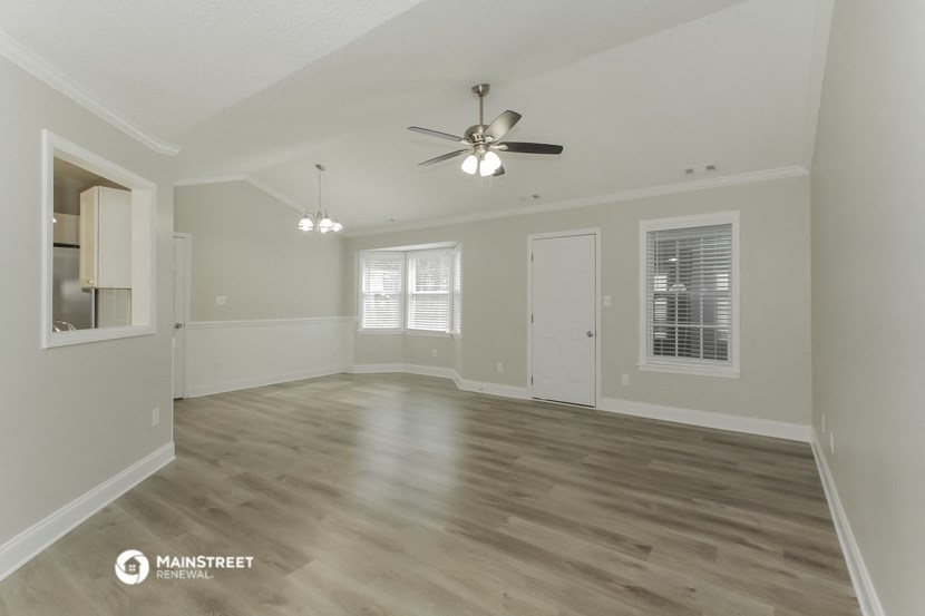 the living room of an empty house with a ceiling fan