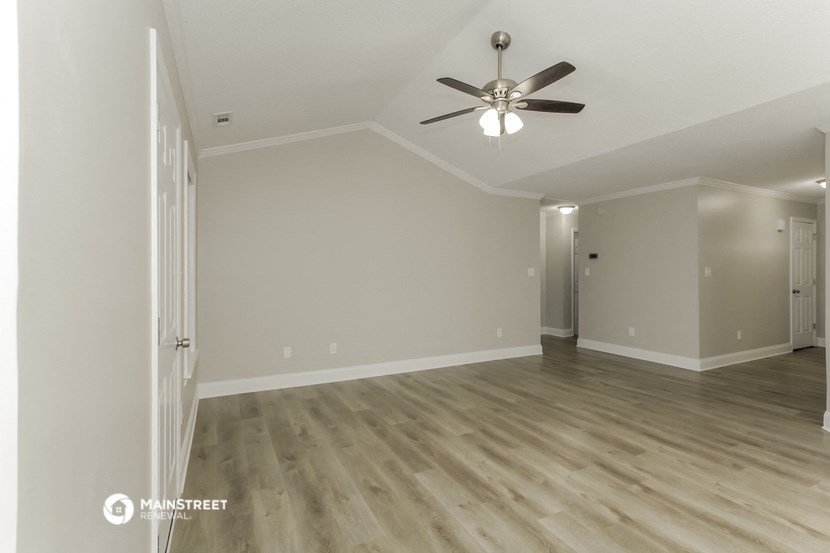the living room of an empty house with a ceiling fan