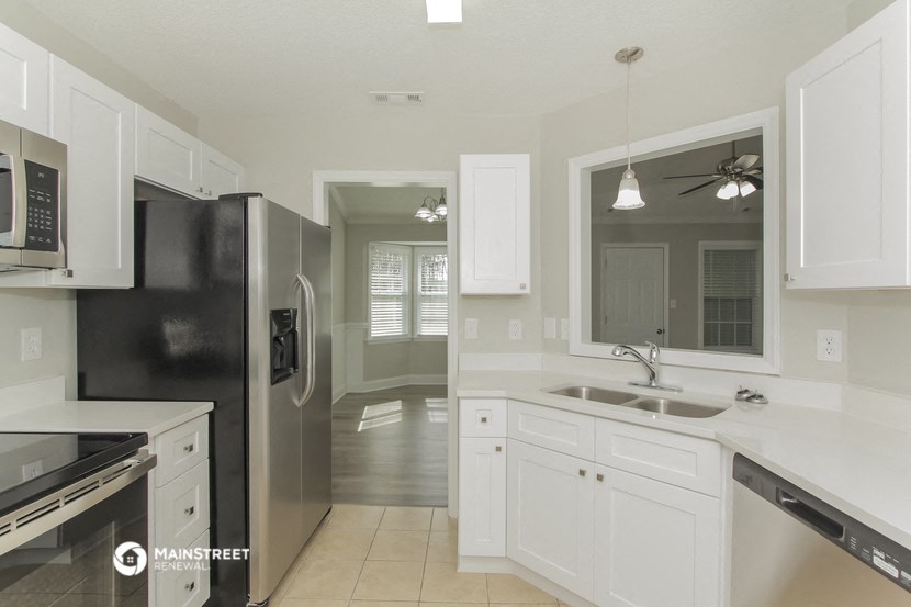 a kitchen with white cabinets and a black refrigerator and a sink