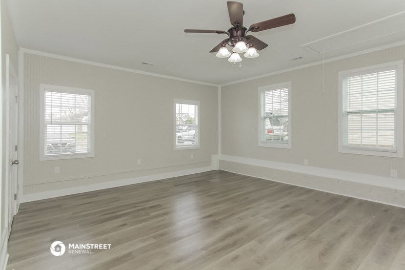 the spacious living room of a new home with a ceiling fan