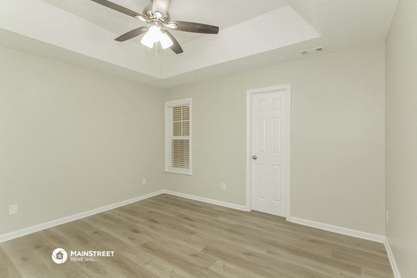 the spacious living room with hardwood flooring and a ceiling fan