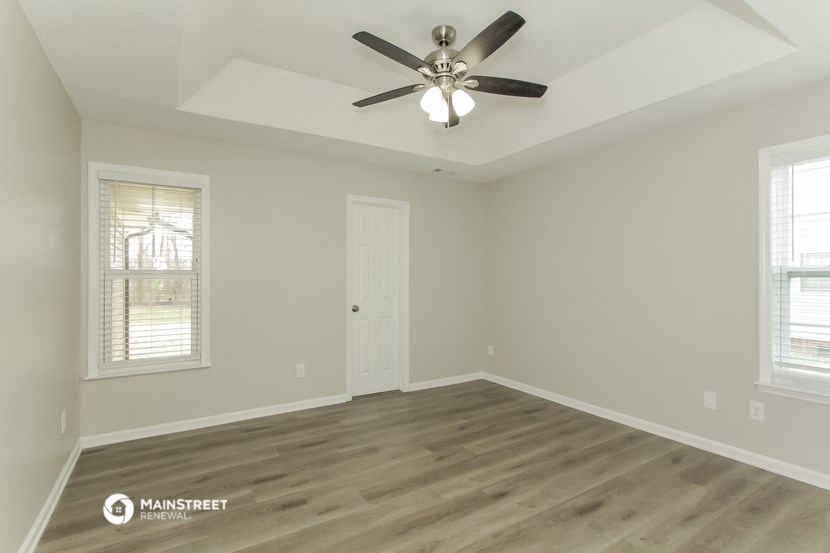 the spacious living room with hardwood floors and a ceiling fan