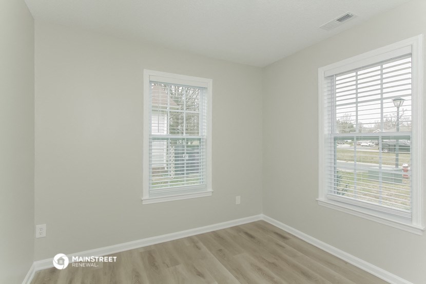 the living room of a new home with wooden floors and two windows