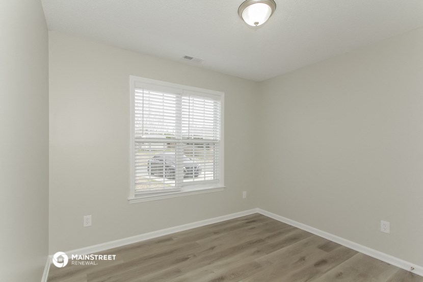 the living room of a manufactured home with wood flooring and a window