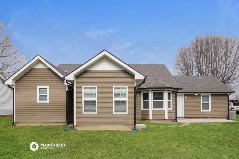 a home with brown siding and white windows on the side of a field