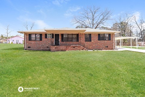 a small brick house with a large lawn in front of it