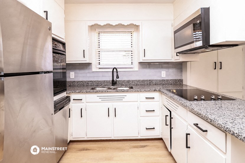 a kitchen with white cabinets and granite counter tops