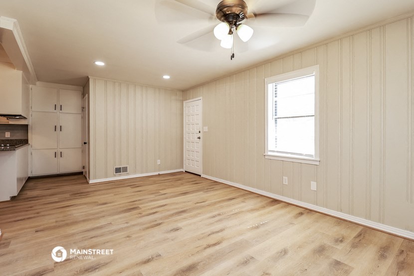 an empty living room with wood flooring and a ceiling fan