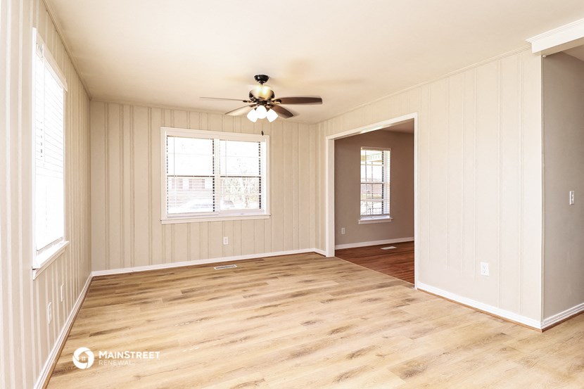 an empty living room with wood floors and a ceiling fan