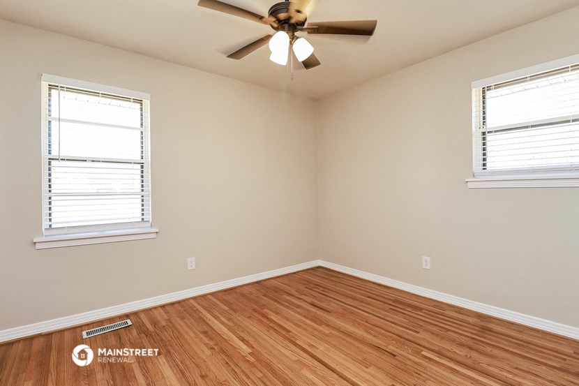the spacious living room with hardwood floors and a ceiling fan