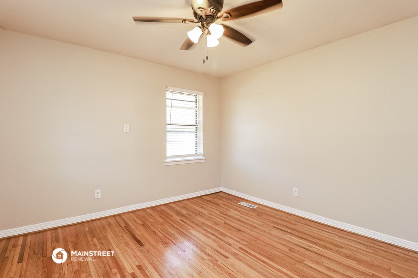 the spacious living room with hardwood floors and a ceiling fan
