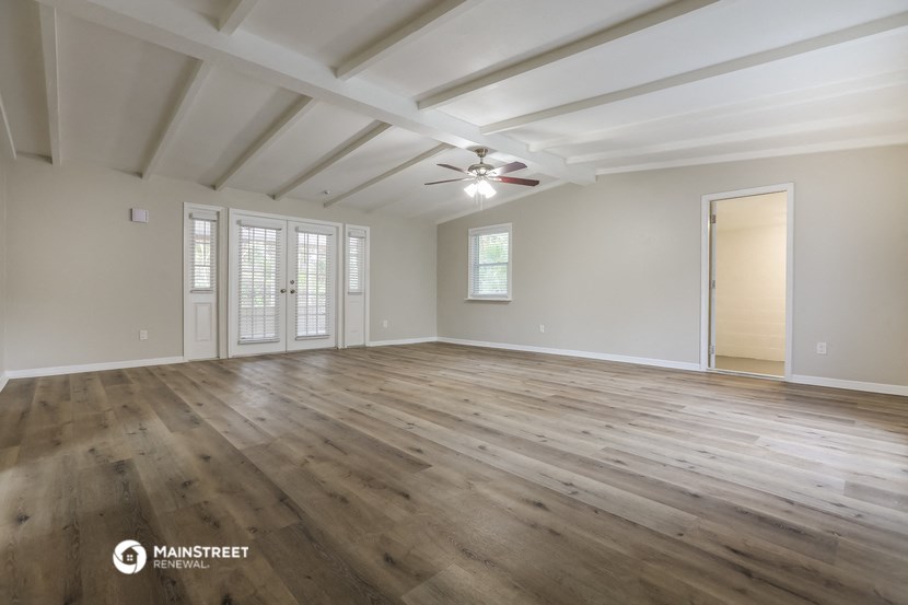 the spacious living room with hardwood floors and a ceiling fan