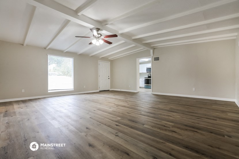 the living room of an empty house with a ceiling fan