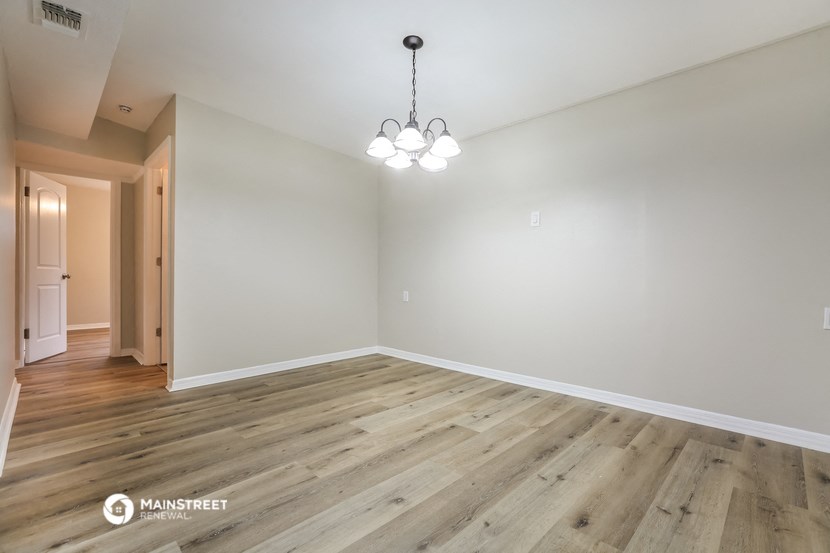 the living room of an empty house with wood floors and a chandelier