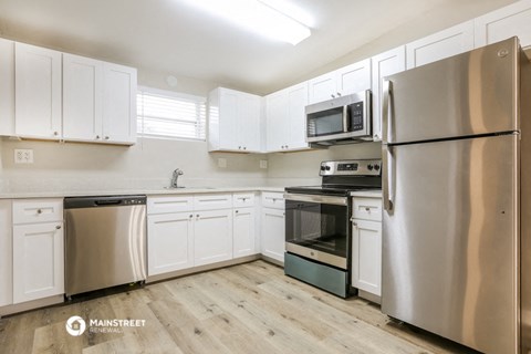 a white kitchen with stainless steel appliances and white cabinets