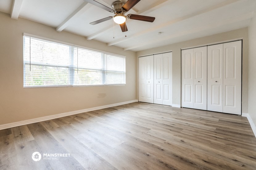 an empty living room with wood floors and a ceiling fan