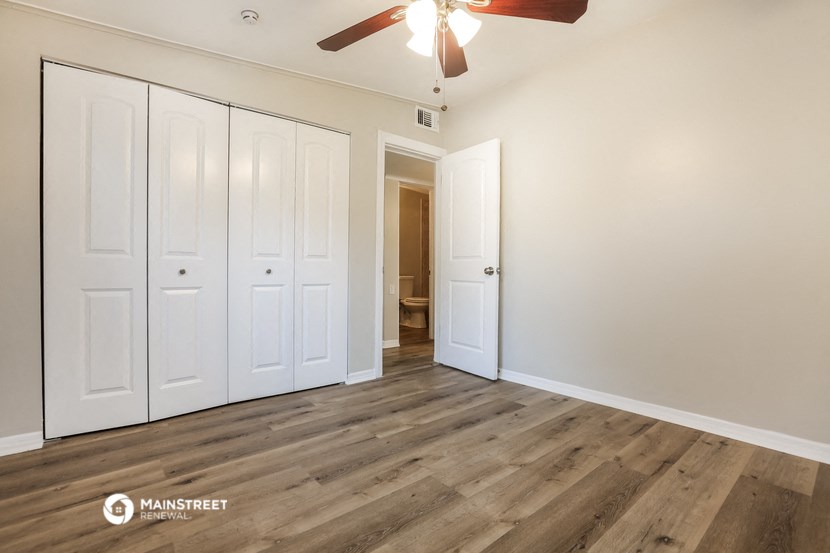 a bedroom with white closets and a ceiling fan