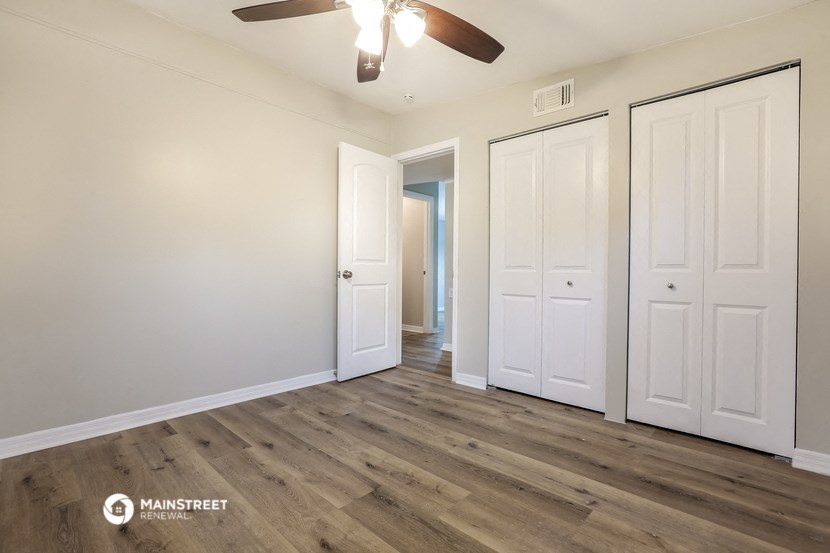 the living room of an apartment with white doors and a ceiling fan