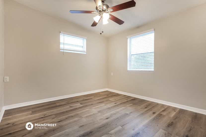 the spacious living room with hardwood floors and a ceiling fan