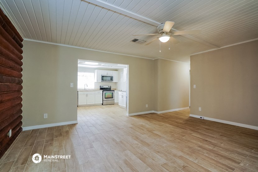 an empty living room with wood floors and a ceiling fan