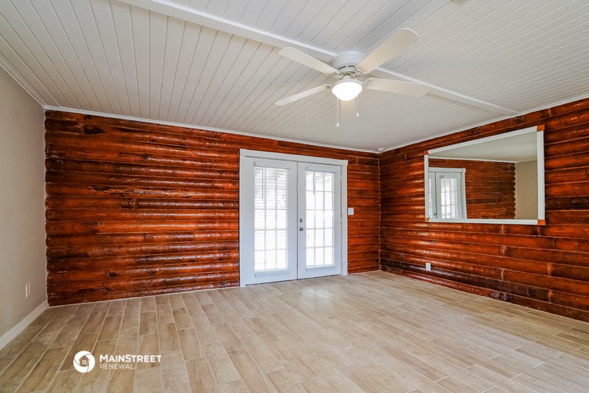 an empty room with wood paneling and a ceiling fan