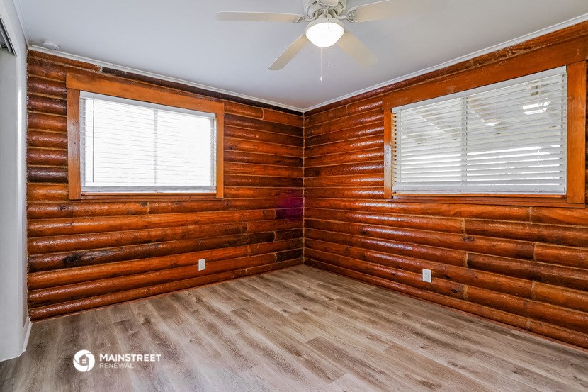 a living room with wooden walls and a ceiling fan