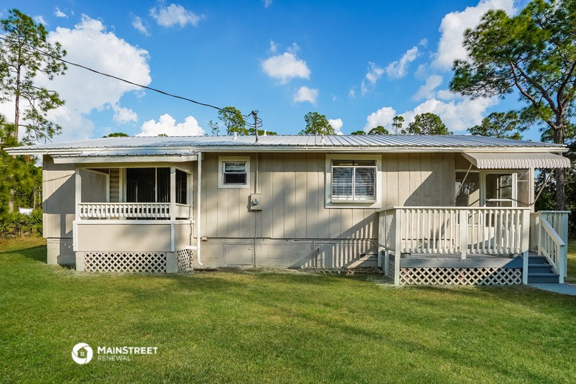 a small gray house with a porch and a lawn