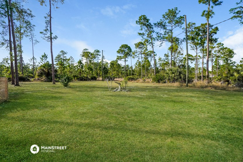 a large grassy field with trees in the background