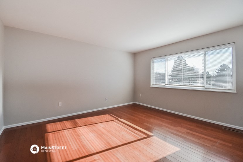 the living room of an apartment with wood floors and a large window