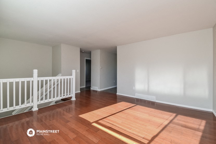 an empty living room with wood floors and a white railing