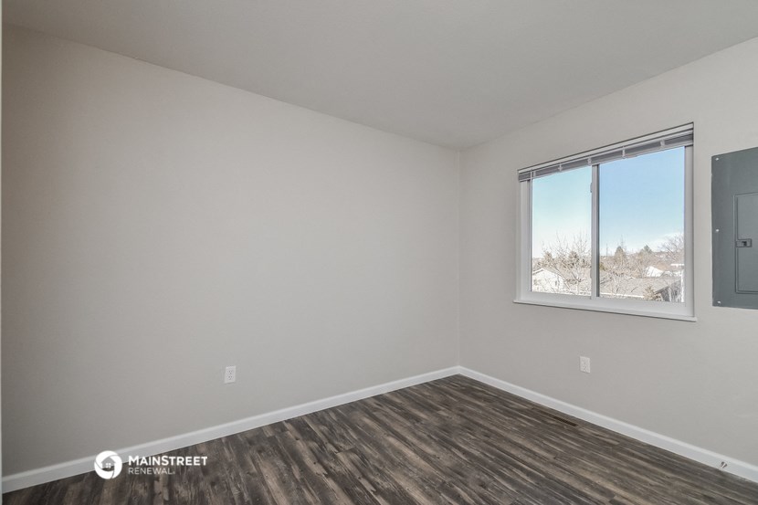 the living room of an apartment with wood flooring and a window